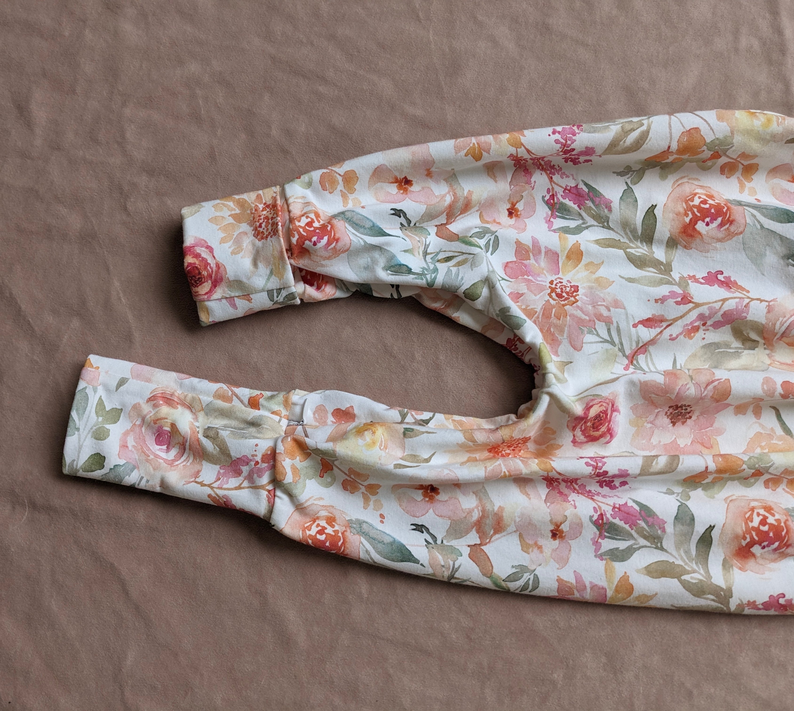 Floral-patterned baby romper on a brown surface
